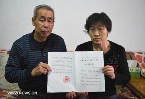 Li Sanren (trái) và Shang Aiyun, cha mẹ của Hugjiltu cho thấy phán quyết bồi thường oan sai hơn hai triệu nhân dân tệ (khoảng 322.000 USD) hồi tháng 12/2014. Ảnh: Xinhua