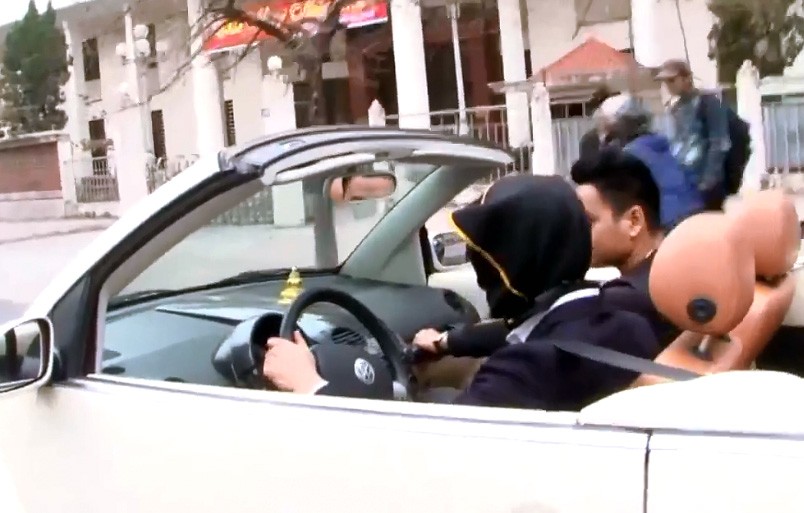 Người đàn ông trùm bao vải đen kín mặt, điều khiên ô tô trên phố Hà Nội. (Ảnh cắt từ clip)