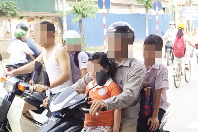 Phụ huynh "kẹp 3" trước cửa trường tiểu học tại Hà Nội trong khi học sinh không đội mũ bảo hiểm. Ảnh: Hạnh Nguyên/Dân Trí