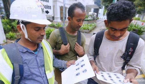 Các công nhân xây dựng xem ảnh 27 công nhân Bangladesh bị bắt ở Malaysia theo đạo luật An ninh Nội địa. Ảnh: Today