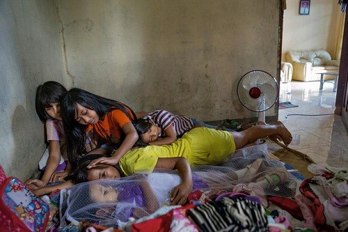 Chị em gái bên cạnh xác của Syahrini Tania Tiranda, bé gái 3 tuổi được phủ khăn voan mới mất một ngày. Các bé ôm ấp và trò chuyện cùng Tiranda, coi em là "makula - người ốm". Ảnh: NG