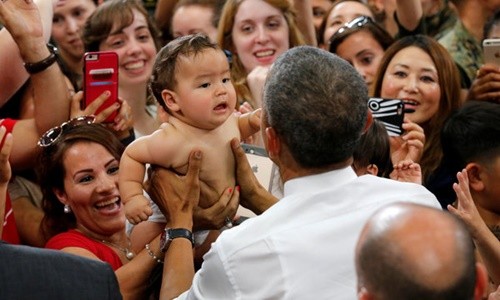 Em bé đã nín khóc sau khi được ông Obama bế. Ảnh: Reuters