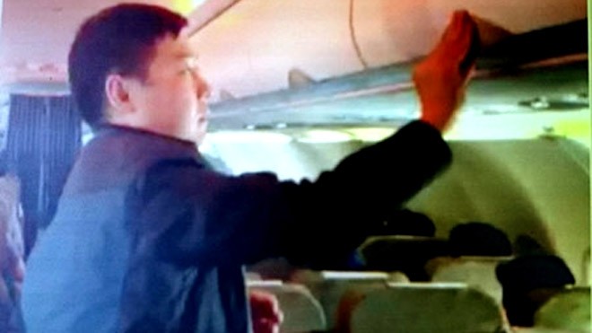 Hình ảnh về cảnh hành khách Zhang Giang (Trung Quốc) ăn cắp đồ tại giá hành lý trên chuyến bay VN 600 Bangkok (Thái Lan) - TP HCM chiều 19/1 - Ảnh cắt từ clip do tiếp viên quay được