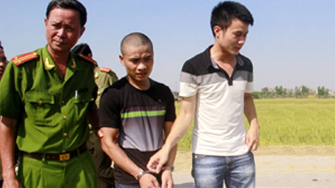 Hung thủ Nguyễn Văn Hải (áo đen) bị cảnh sát áp giải về nơi gây án tìm hung khí chiều 2/6. Ảnh: Lê Hoàng