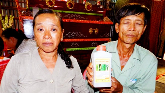 Vợ chồng ông Nguyễn Văn Tổng bên chai thuốc trừ sâu mà Kiệt dùng để tự tử