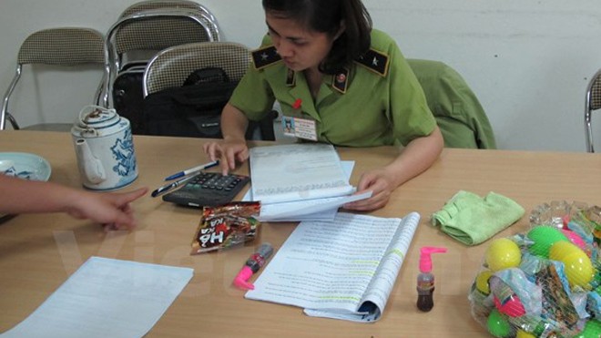 Lực lượng Quản lý thị trường Hà Nội đang lập biên bản thu giữ số bánh kẹo nhập lậu. Ảnh: Đức Duy/Vietnam+