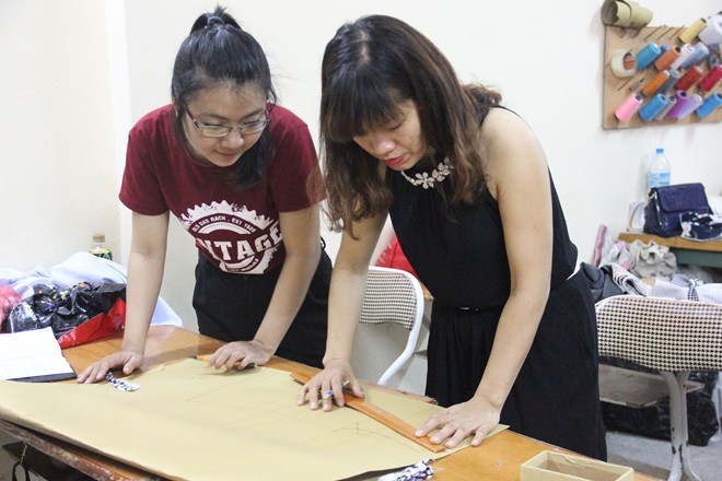 Chị Hoa hướng dẫn học viên cách vẽ, đo và cắt may trên vải ngay từ buổi học đầu tiên. Ảnh: Ngọc Lan