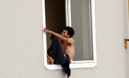 Vũ Văn Tuyền ngồi cheo leo trên cửa sổ tầng 21 chung cư Packexim