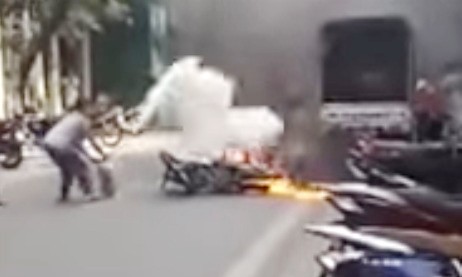 Bà Huệ dùng bình cứu hỏa mini dập tắt đám cháy xe máy trên phố Hàng Nón trưa 21/11. Ảnh cắt từ clip