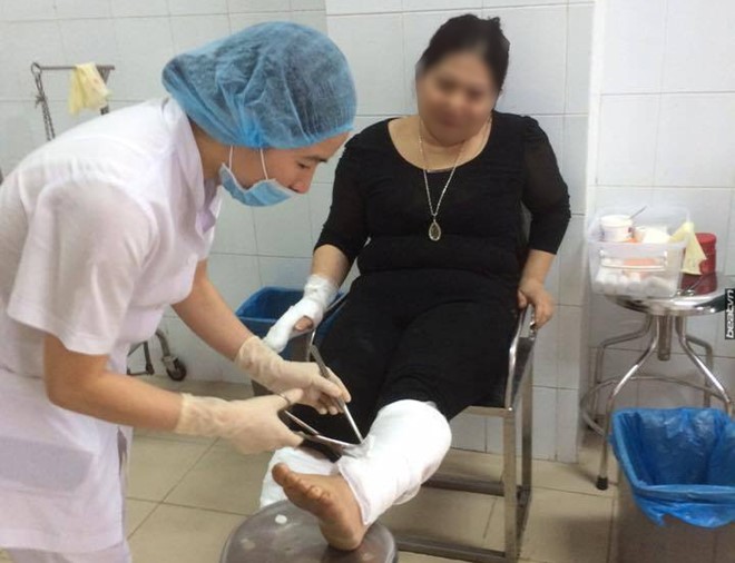 Chị Hương bị bỏng ở chân và tay đang được bác sĩ sơ cứu. Ảnh: Beat.vn