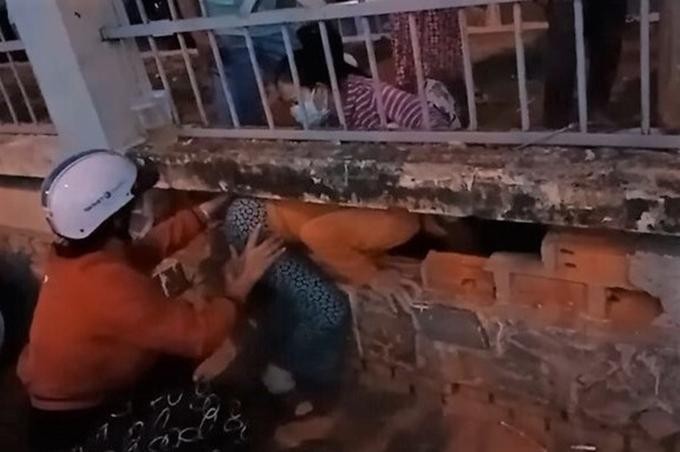Các phụ nữ đang chui lỗ tường rào thoát ra bệnh viện, đêm 1/7. Ảnh: Cắt từ video người dân cung cấp/VnExpress