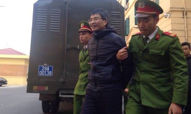 Giang Kim Đạt tươi cười khi bị dẫn giải tới tòa.