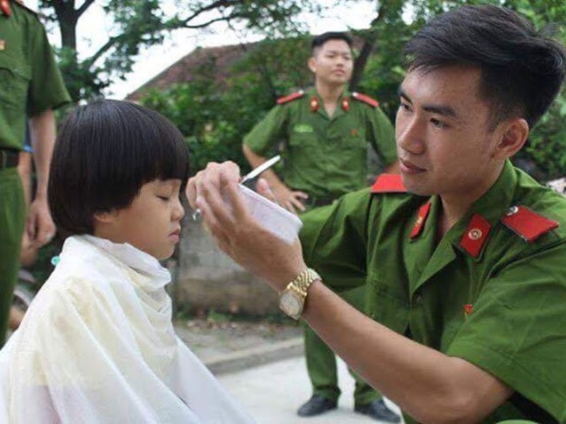 Chiến sĩ cảnh sát trổ tài cắt tóc cho các em thiếu nhi.