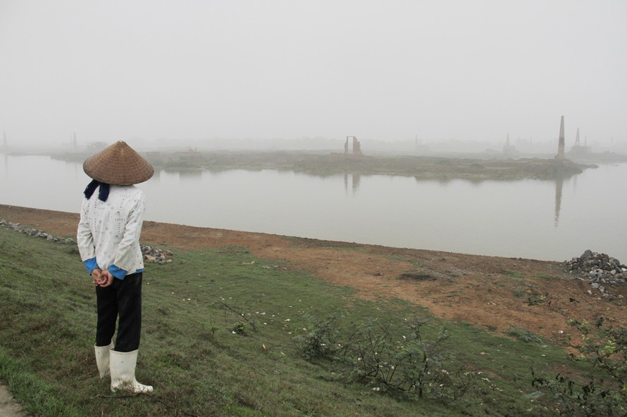 Một phụ nữ đứng trên đoạn đê mới được kè đá do bị sạt lở trên địa bàn xã Quế Tân (Quế Võ, Bắc Ninh). Ảnh: Trường Phong