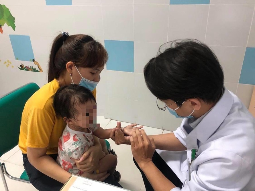 Bác sĩ khám cho một trẻ bị mắc tay chân miệng