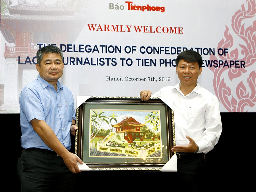 Phó Tổng Biên tập báo Tiền Phong Trần Thanh Lâm tặng quà lưu niệm đoàn đại biểu nhà báo Lào.