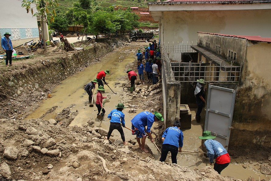 Các tình nguyện viên dọn dẹp bùn đất khu vực trường học và nhà sinh hoạt cộng đồng