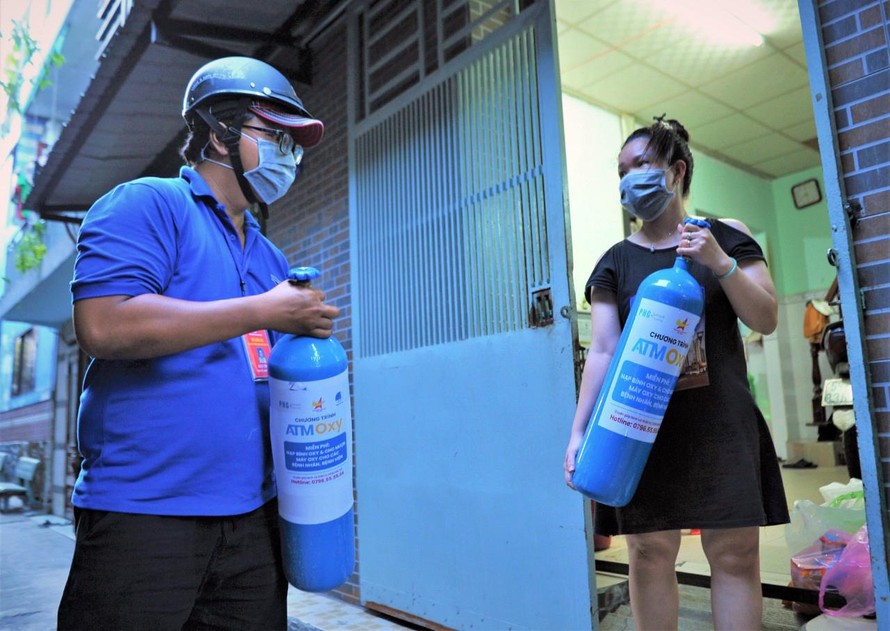 Các tình nguyện viên mang bình oxy đến cho những người cần sử dụng. - Ảnh: Nguyễn Á