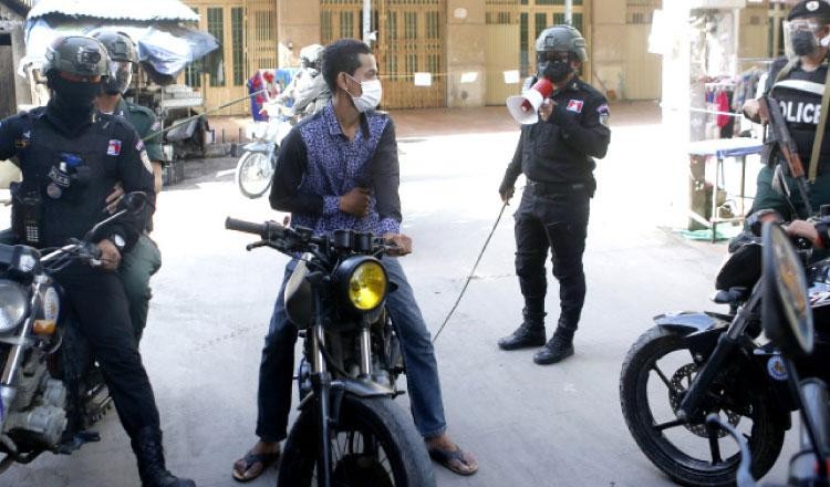 Cảnh sát mang roi bao vây một người đi xe máy trong “khu vực đỏ” về dịch COVID ở quận Meanchey của thủ đô Phnom Penh.