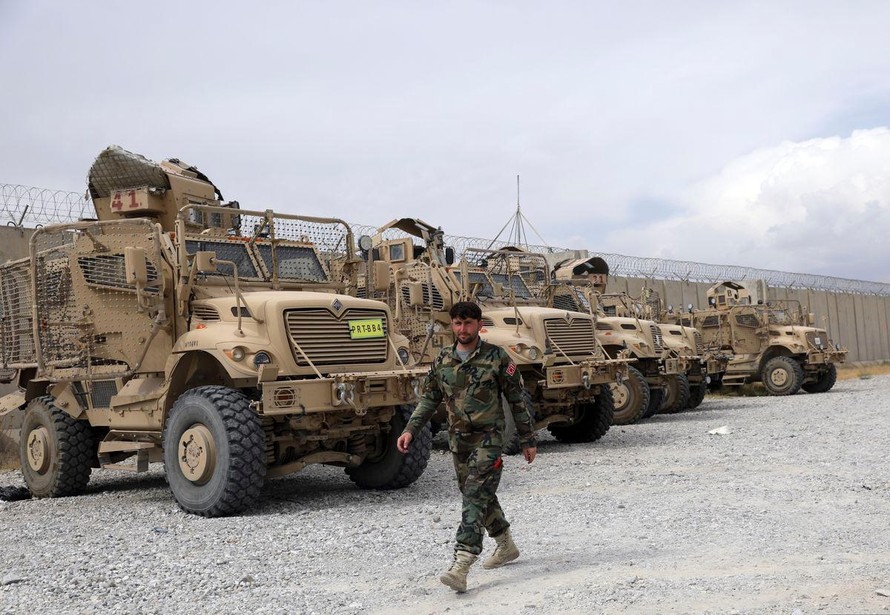 Một binh sĩ quân đội Afghanistan đi ngang qua các phương tiện chống mìn MRAP, bị bỏ lại sau khi quân đội Mỹ rời căn cứ không quân Bagram, ở tỉnh Parwan, phía bắc Kabul, Afghanistan, ngày 5 tháng 7 năm 2021. Quân Mỹ rời Sân bay Bagram của Afghanistan sau gần gần 20 năm đồn trú.