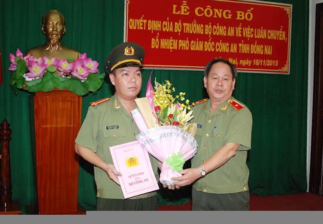 Thiếu tướng Nguyễn Thanh Nam (bìa phải) trao quyết định và tặng hoa chúc mừng Trung tá Lê Hoàng Ngân. Ảnh: Báo Đồng Nai 