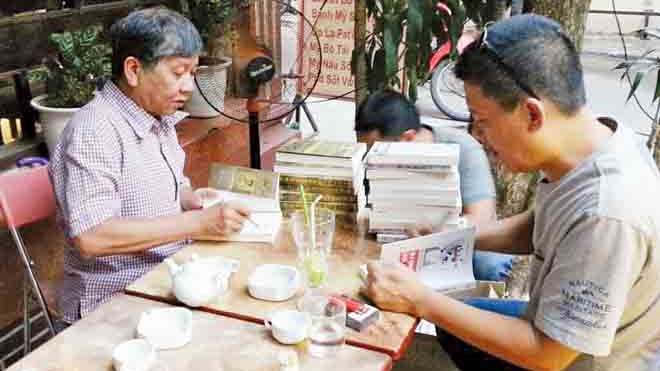 Nguyễn Việt Hà (phải) đang ký sẵn vào 4 đầu sách tặng bạn đọc. Đối diện là bạn văn Nguyễn Huy Thiệp. ảnh: n.t.quý