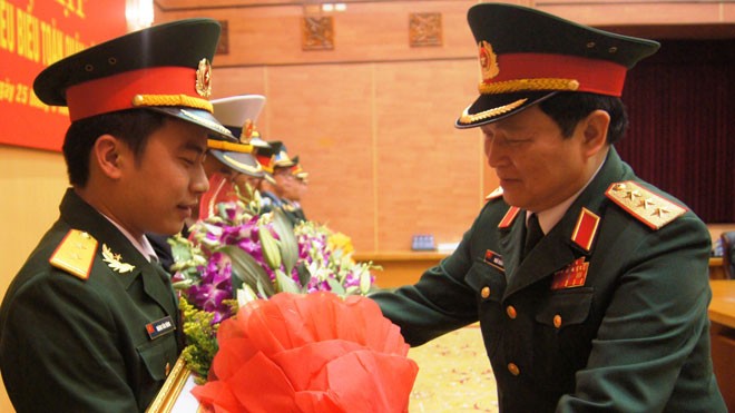 Thượng tướng Ngô Xuân Lịch (bên phải), Bí thư T.Ư Đảng, Chủ nhiệm Tổng cục Chính trị trao bằng khen và tặng hoa chúc mừng Trung úy Hoàng Văn Đông, tháng 3/2014. ảnh: NGUYỄN MINH