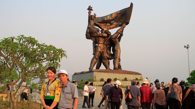 Chị Lò Thị Toản chụp ảnh lưu niệm với khách du lịch bên tượng đài chiến thắng Điện Biên Phủ