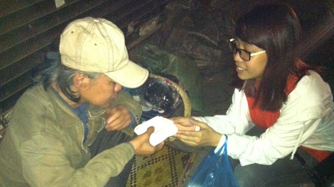 Sinh viên CLB Kỹ năng sống trường Đại học Ngoại thương tặng xôi cho bà cụ trên đường phố Hà Nội đêm 30/4. Ảnh: Hữu Thắng