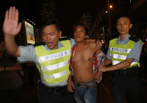 Cảnh sát Hong Kong áp giải một thanh niên phá hàng rào để xông vào trại của người biểu tình tại quận Mongkok hôm qua. Ảnh: Reuters