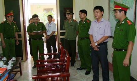 Lê Chí Lam (người mặc thường phục) nghe đọc quyết định khởi tố của Cơ quan Điều tra. Ảnh: Báo Thanh tra.