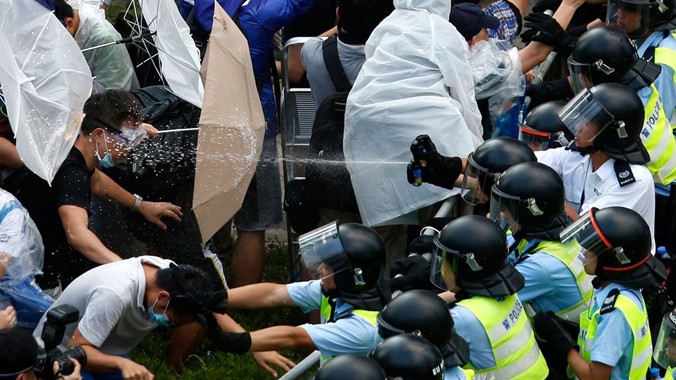 Một người biểu tình Hong Kong bị cảnh sát xịt thẳng hơi cay vào mặt. Ảnh: Business Insider