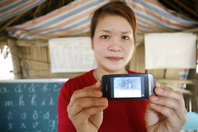 Cô giáo Tòng Thị Minh giơ cho phóng viên xem điện thoại và videoclip qua suối bằng túi nilon (ảnh Thái Anh)