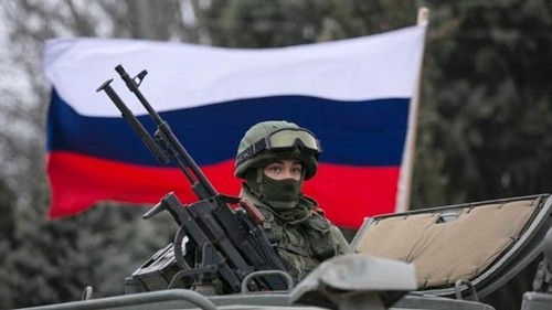 Một binh sĩ ở Crimea đứng trước lá cờ Nga. Ảnh: Reuters