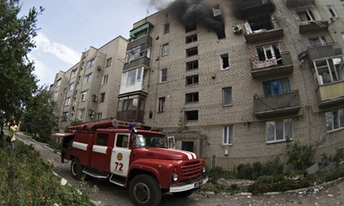 Xe cứu hỏa tới hiện trường một tòa nhà cháy sau một vụ nã pháo vào làng Maryinka, gần khu vực Donetsk, miền đông Ukraine. Ảnh: AP 