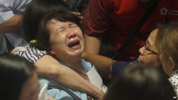 Thân nhân hành khách đi chuyến bay QZ8501 của AirAsia khóc ngất khi trông thấy tivi phát đi hình ảnh các thi thể trên biển. Ảnh: AP.