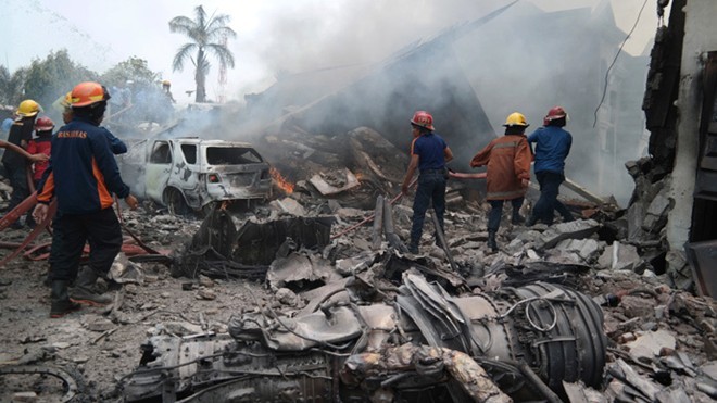 Nhân viên cứu hỏa cố gắng dập tắt ngọn lửa quanh đống đổ nát sau khi máy bay vận tải Hercules C-130 rơi tại thành phố Medan hôm 30/6 chỉ vài phút sau khi cất cánh. Ảnh: Reuters