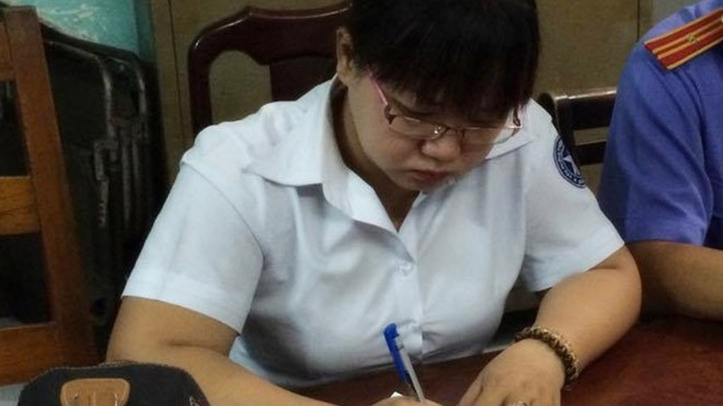 Bà Đào đang ký vào biên bản làm việc của Cơ quan điều tra sáng 18/11. Ảnh: Tân Châu