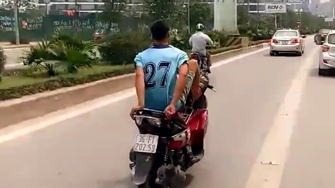 Nam thanh niên "trổ tài" điều khiển xe máy bằng chân. (Ảnh cắt từ clip)