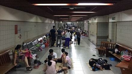 Bệnh nhân và người nhà trải chiếu nằm dọc hành lang bệnh viện Bạch Mai để tránh nóng.