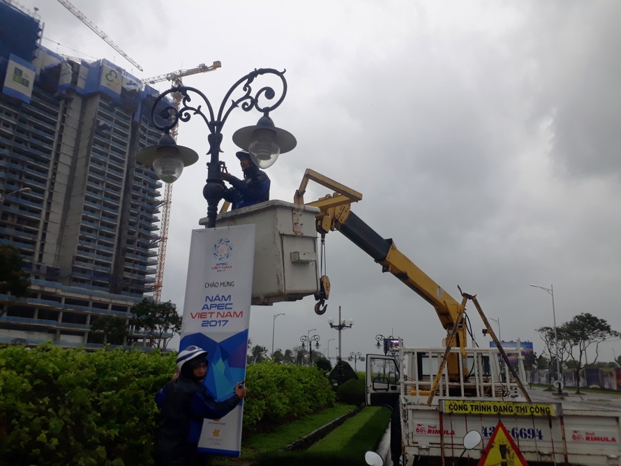 Công nhân sửa chữa thay thế các pano chào mừng APEC trên đường Phạm Văn Đồng. Ảnh: Nguyễn Thành