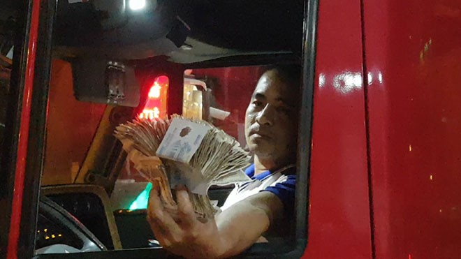 Nhân viên quầy vé đưa tờ tiền 100 đồng thừa cho tài xế (Ảnh Nhật Huy)