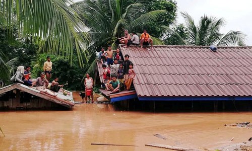 Người dân ở tỉnh Attapeu phải tạm trú trên mái nhà do ngập lụt ngày 24/7. Ảnh: Reuters. 