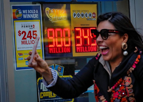 Một phụ nữ đi qua bảng hiệu thông báo giải độc đắc của Mega Millions và Powerball tại văn phòng xổ số bang New York hôm 17/10. Ảnh: Reuters