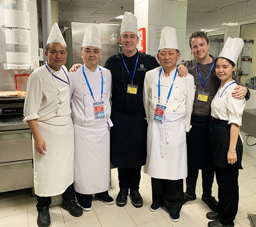 Bếp trưởng Paul Smart (thứ ba từ trái sang) chụp ảnh lưu niệm cùng đầu bếp Triều Tiên, phiên dịch và người giám sát của hai phía. 