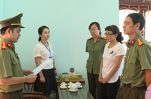 Bị can Nguyễn Thị Hồng Nga (áo trắng bên phải) nghe tống đạt quyết định khởi tố.