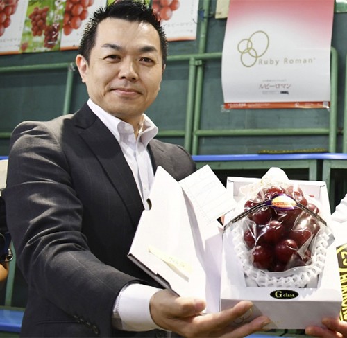 Takashi Hosokawa và chùm nho ông mua với giá 11.000 USD trong phiên đấu giá hôm 9/7. Ảnh: Kyodo 