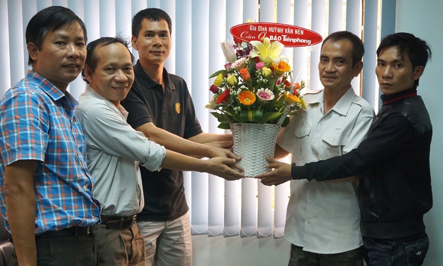 Ông Huỳnh Văn Nén và anh Huỳnh Thành Lượng, con trai thứ hai của ông Nén (bên phải) tặng hoa cảm ơn báo Tiền Phong. 