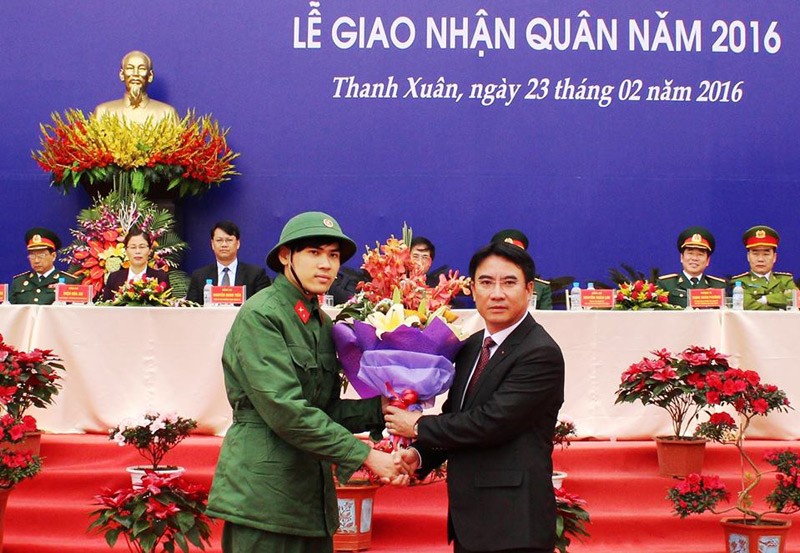 Chủ tịch UBND quận Thanh Xuân Nguyễn Xuân Lưu tặng hoa cho tân binh Ngô Quang Huy tại lễ giao, nhận quân. (Ảnh: Hồng Thái).
