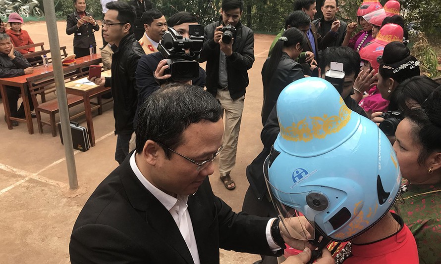 Ông Khuất Việt Hùng, Phó Chủ tịch Uỷ ban ATGT quốc gia trao tặng mũ bảo hiểm cho phụ nữ dân tộc Thái.